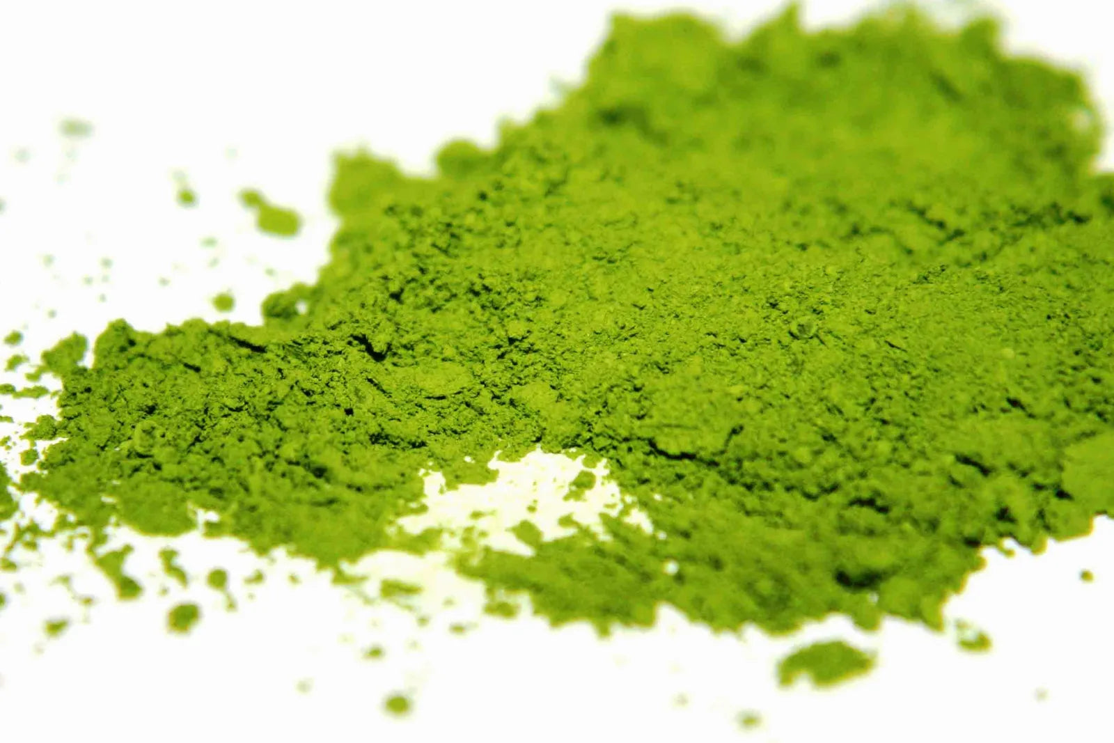 Vibrant green matcha powder in a close-up macro shot showing fine texture on a white surface